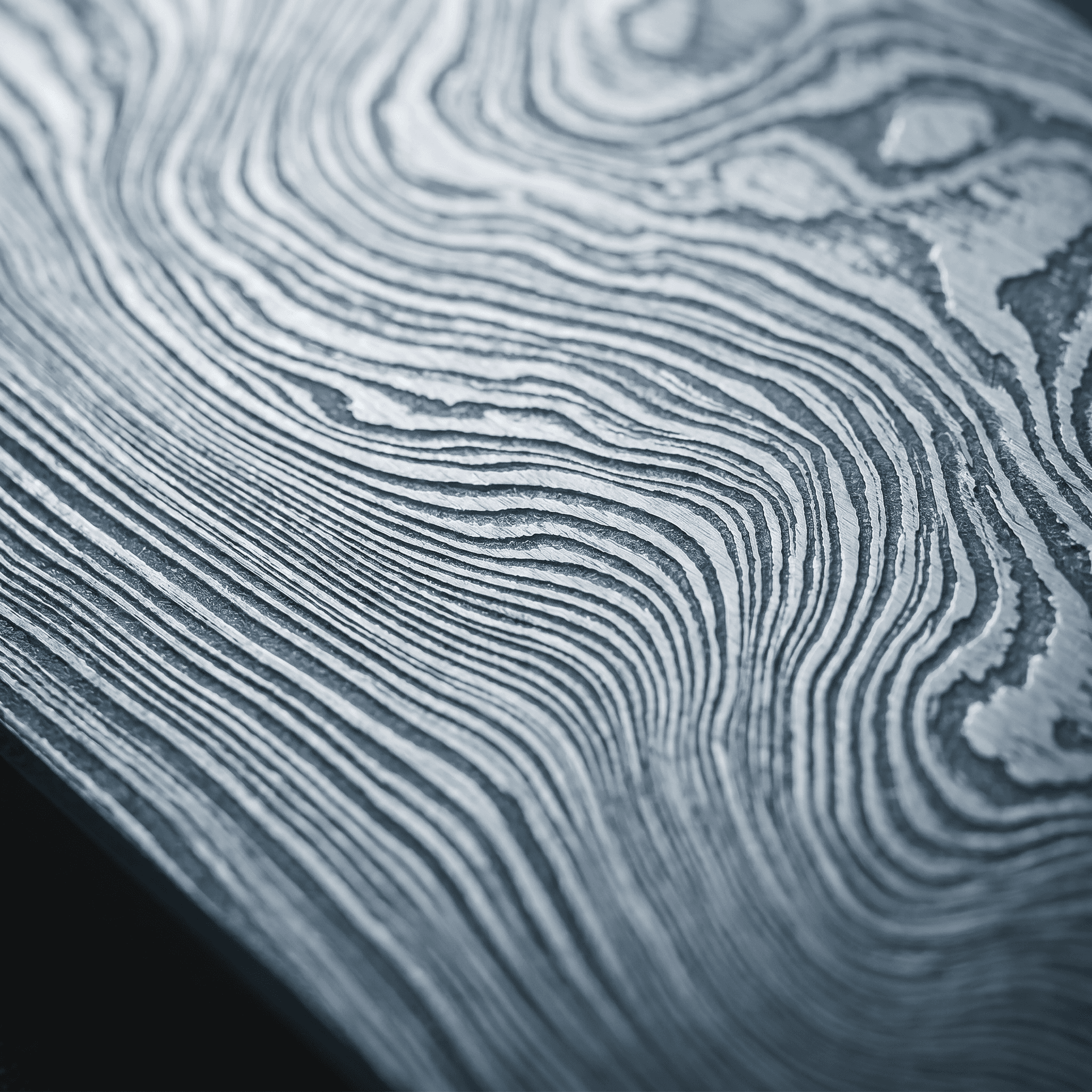 Macro d'acier Damas : motif de couches ondulées révélé à l'acide.
